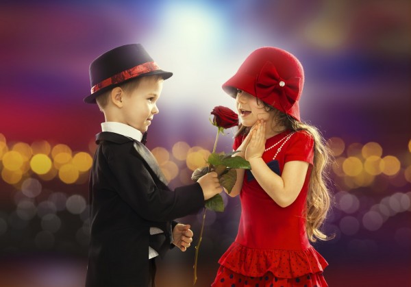 Lovely little boy giving a rose to fashionable girl and her excited