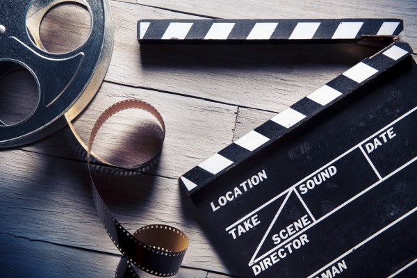 Movie clapper and film reel on a wooden backgorund