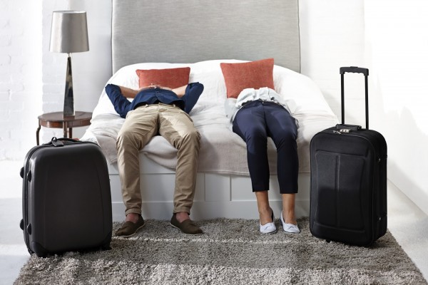 Indoor shot of mature couple lying on bed with luggage