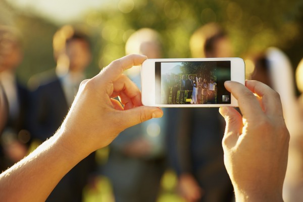 Shot of a wedding guest taking a photo at the reception