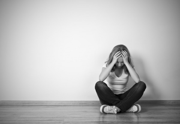 girl sits in a depression on the floor near the wall monochrome