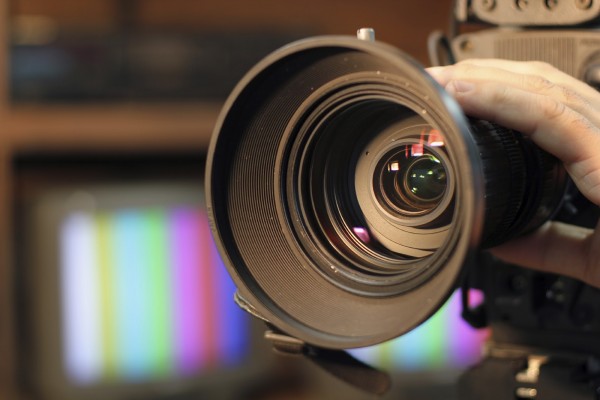 Closeup shot of professional video camera, with its lens zooming in.