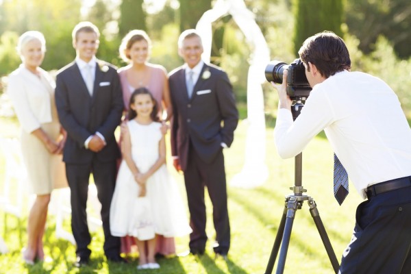 Young man photographing family at outdoor wedding. Horizontal shot.