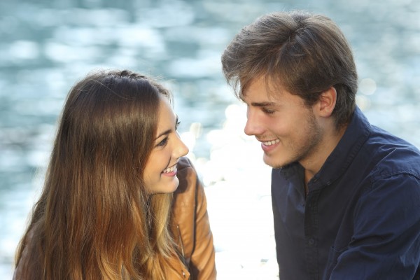 Couple looking each other in love on vacations with the sea in the background