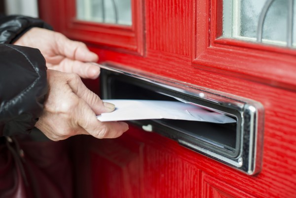 Hand putting Letter in a red mailbox.