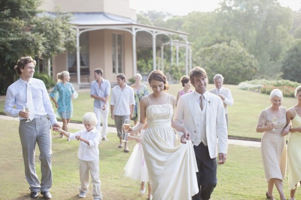 Bride, groom and guests walking across lawn