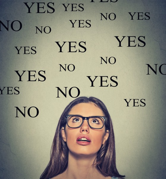 Thinking young woman with yes or no choice looking up on grey wall background