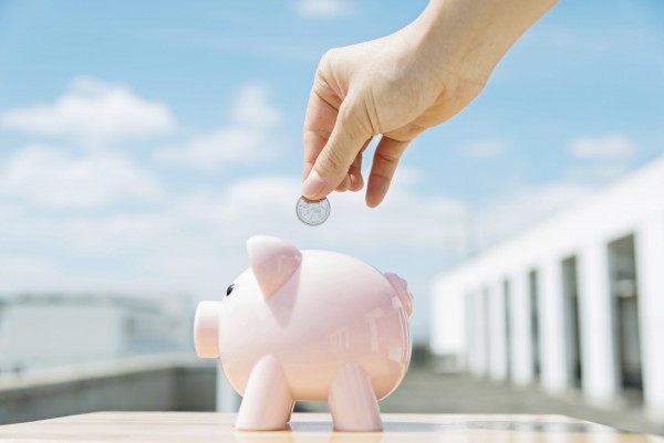 Human hand insert a coin in a pink piggy bank.