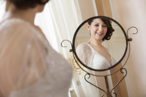 bride smiles in front of the mirror