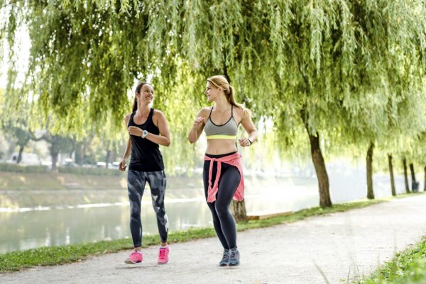 Women (25, 30s) quickly walking in park, power walking.