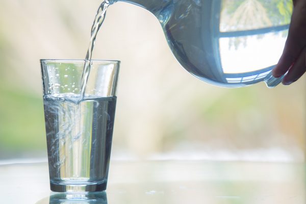 Water being poured from a glass pitcher into a glass.