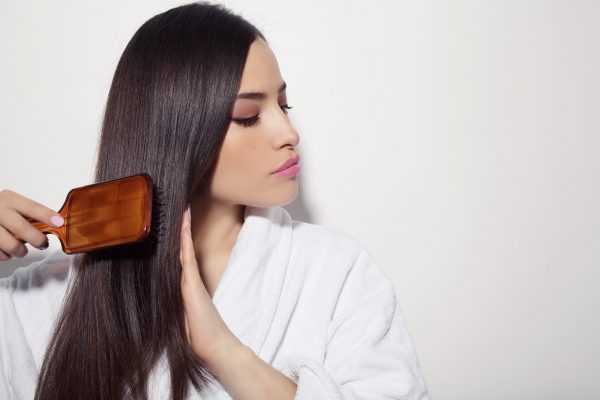 beautiful young woman combing her healthy and shiny hair, studio white