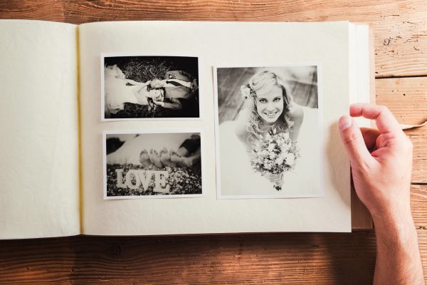 Picture of bride and groom in photo album. Studio shot on wooden background.