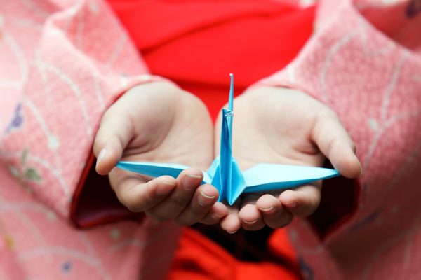 Girl hands holding an origami crane, focus on bird