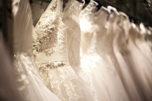 A shopping rack full of white wedding dresses with different styles and sizes.