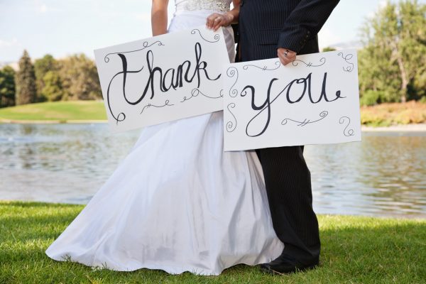 Young Wedding Couple Holding Thank You Signs. Focus is best on the signs.