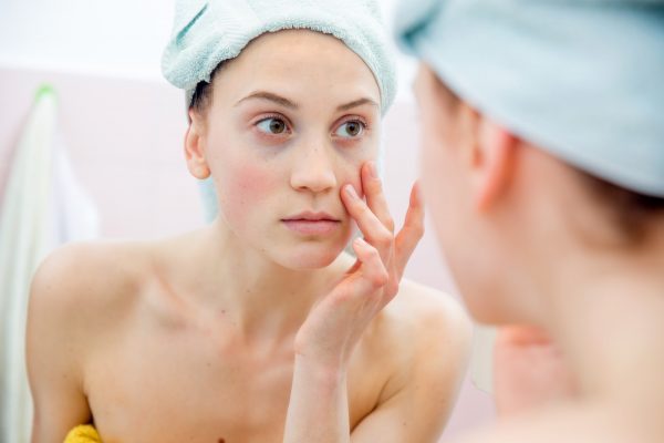 Young woman portrait in the mirror of her bathroom after taking shower.